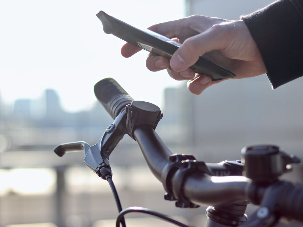 Supporto Shapeheart in procinto di essere fissato sul manubrio di una bicicletta, grazie ai potenti magneti Shapeheart.