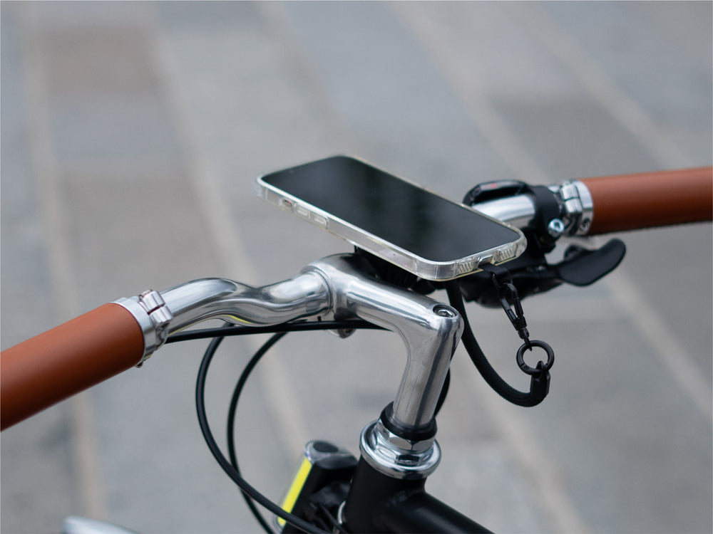 Smartphone fissato magneticamente al supporto manubrio, che dimostra un'installazione minimalista. Utilizzo del cordino per una maggiore sicurezza