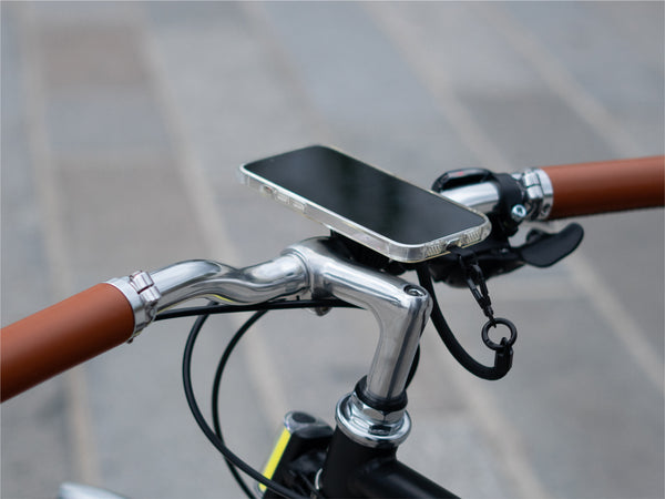 Smartphone fissato magneticamente al supporto manubrio, che dimostra un'installazione minimalista. Utilizzo del cordino per una maggiore sicurezza
