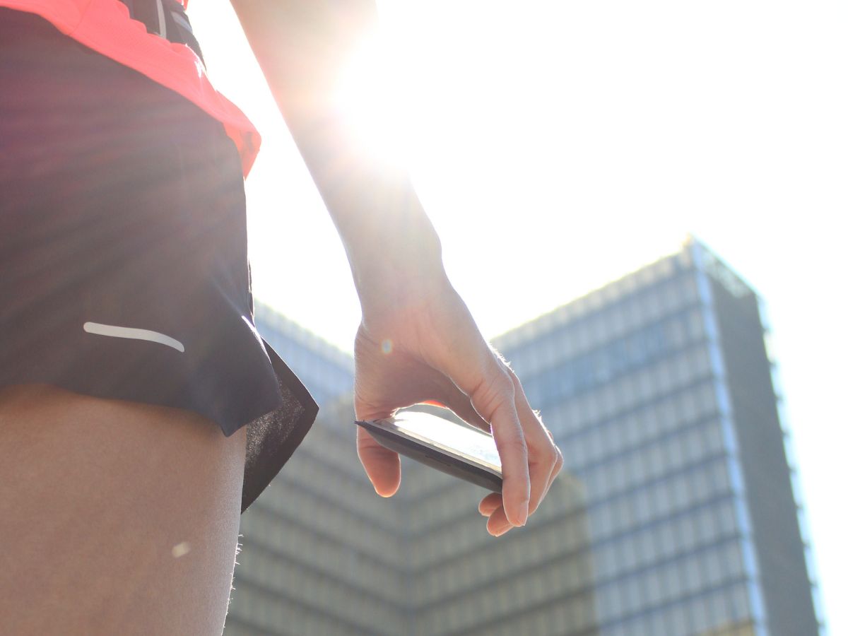 Corridrice in abbigliamento leggero che corre all'alba con una cintura da running contenente una piccola borraccia, simbolo dell'idratazione estiva.