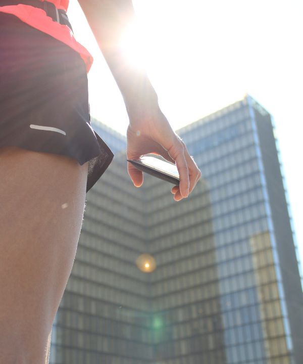 Corridrice in abbigliamento leggero che corre all'alba con una cintura da running contenente una piccola borraccia, simbolo dell'idratazione estiva.