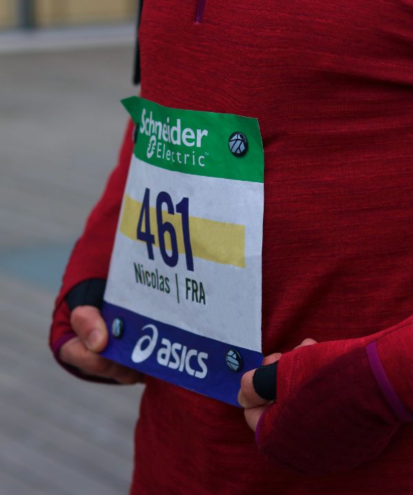 Atleta alla partenza di una competizione con un pettorale tenuto da magneti su una maglia tecnica, che illustra la preparazione ottimale per una gara ufficiale.