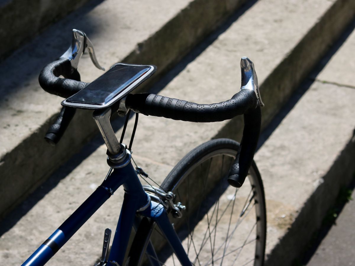 Supporto smartphone magnetico fissato sul manubrio di una bici da strada, con un'app GPS in azione.