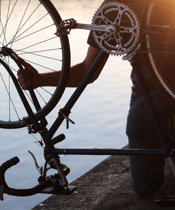 Ciclista che ferma la bici per riparare una foratura, con una mini-pompa e una camera d'aria ai suoi piedi.