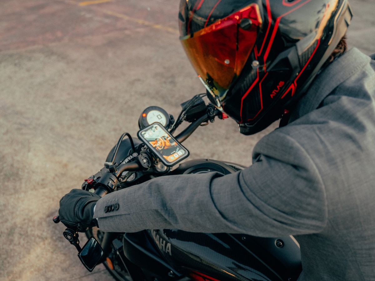 Contenuto minimalista di una borsa da motociclista: guanti, antifurto compatto, powerbank.