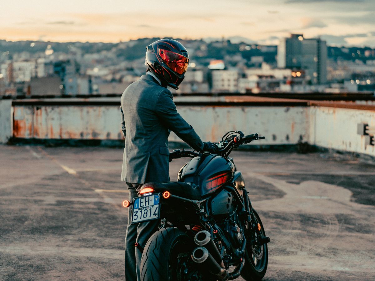 Motociclista che scende dalla moto e ripone rapidamente le sue cose all'arrivo.