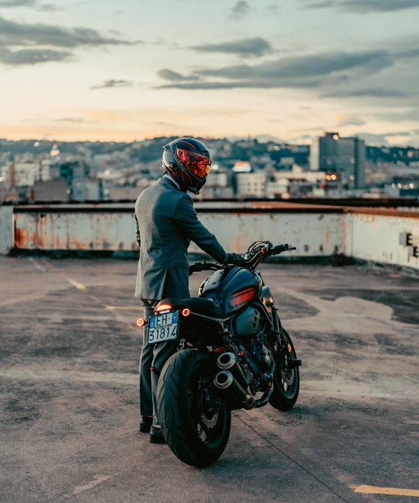 Motociclista che scende dalla moto e ripone rapidamente le sue cose all'arrivo.