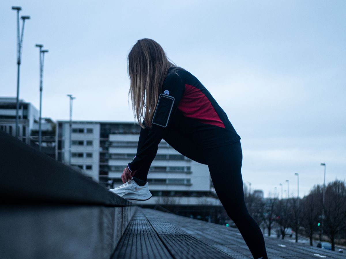 Runner che ascolta musica con auricolari wireless durante un allenamento.
