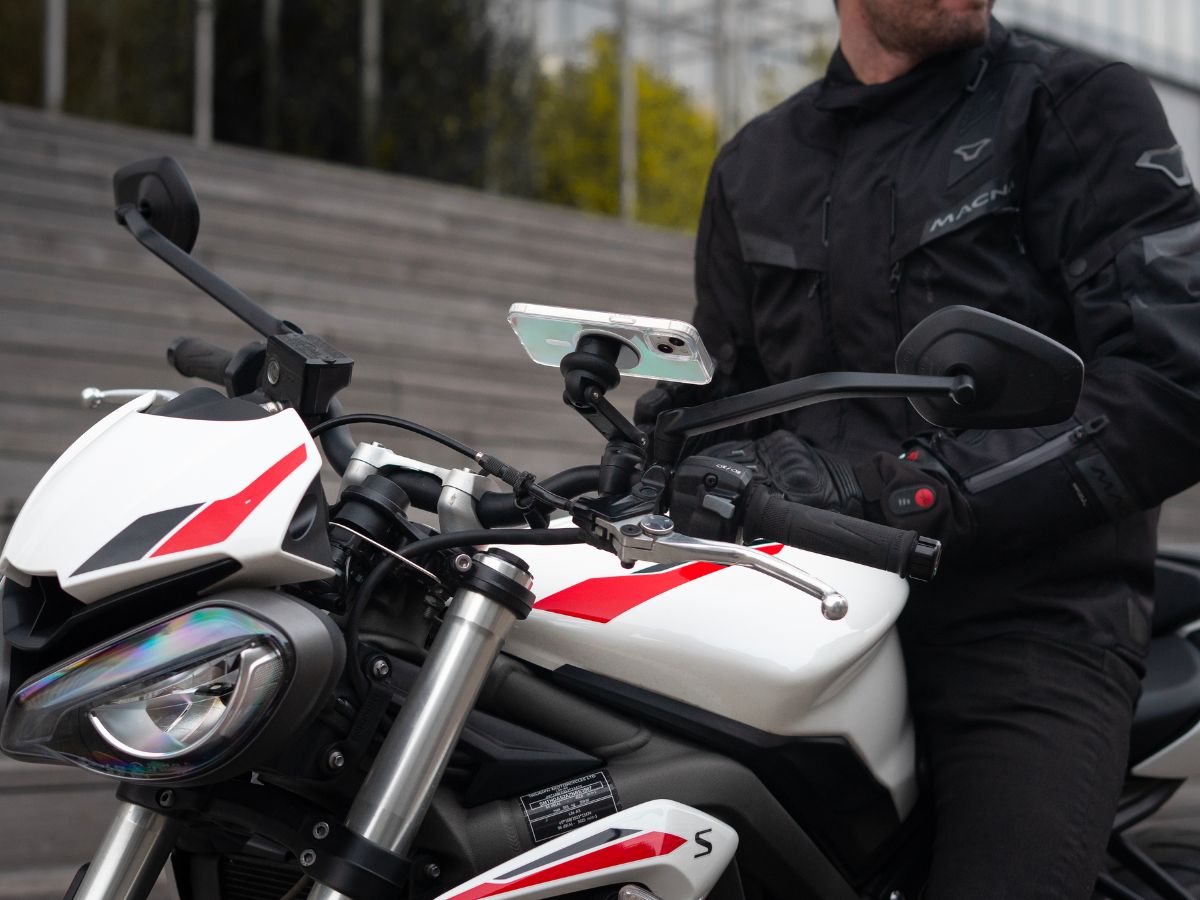 Un motociclista sulla strada che guarda il suo specchietto retrovisore per anticipare il traffico intorno a lui. Una scena che riflette l'importanza di una vigilanza costante in ambiente urbano.