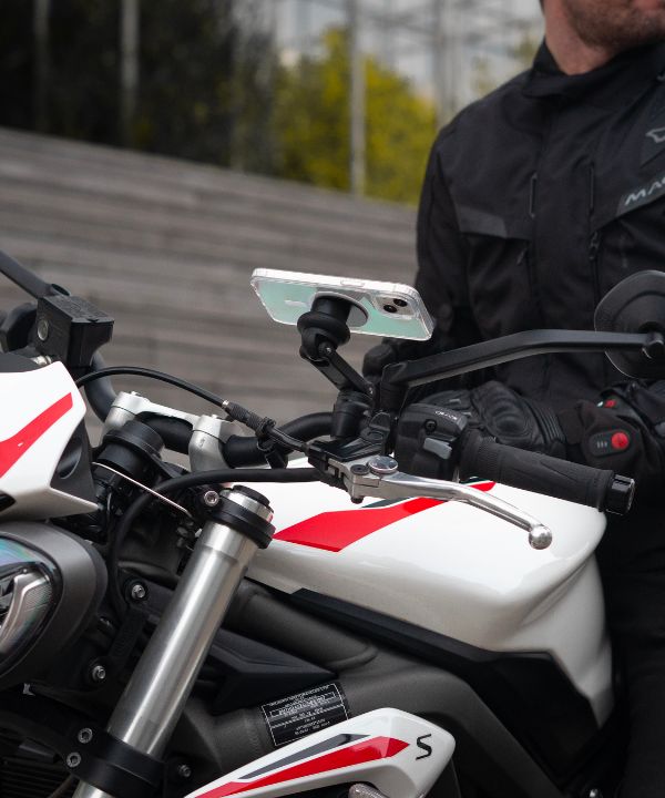 Un motociclista sulla strada che guarda il suo specchietto retrovisore per anticipare il traffico intorno a lui. Una scena che riflette l'importanza di una vigilanza costante in ambiente urbano.