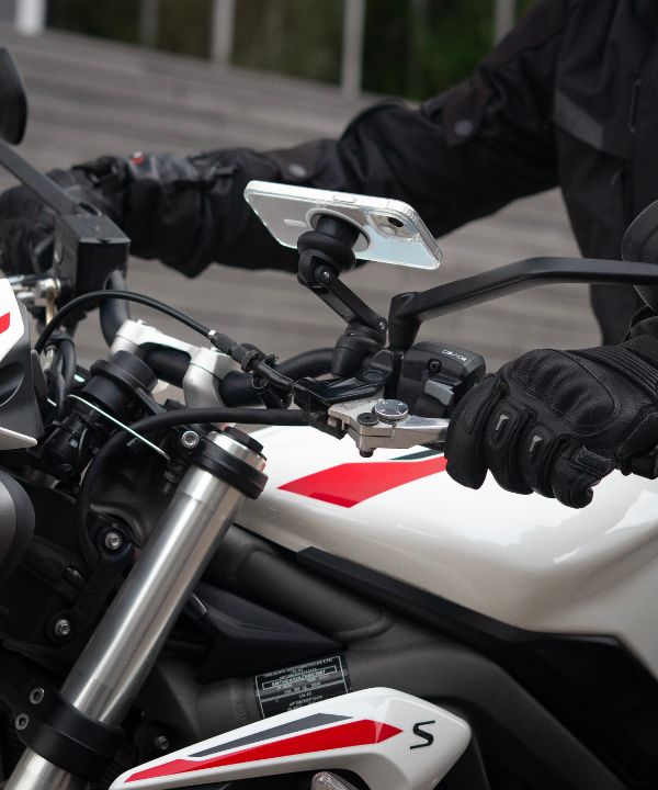 Un semaforo rosso con un motociclista pronto a ripartire, che illustra la necessità di padroneggiare le partenze. La postura del motociclista mostra la sua concentrazione prima di riprendere la strada.
