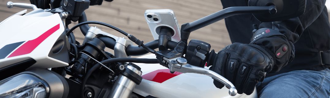 Motociclista principiante che tiene il casco vicino alla sua moto, illustrando la scelta decisiva del primo due ruote dopo aver ottenuto la patente A2.