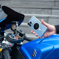 Smartphone con piastra metallica Shapeheart tenuto davanti al manubrio di una moto sportiva