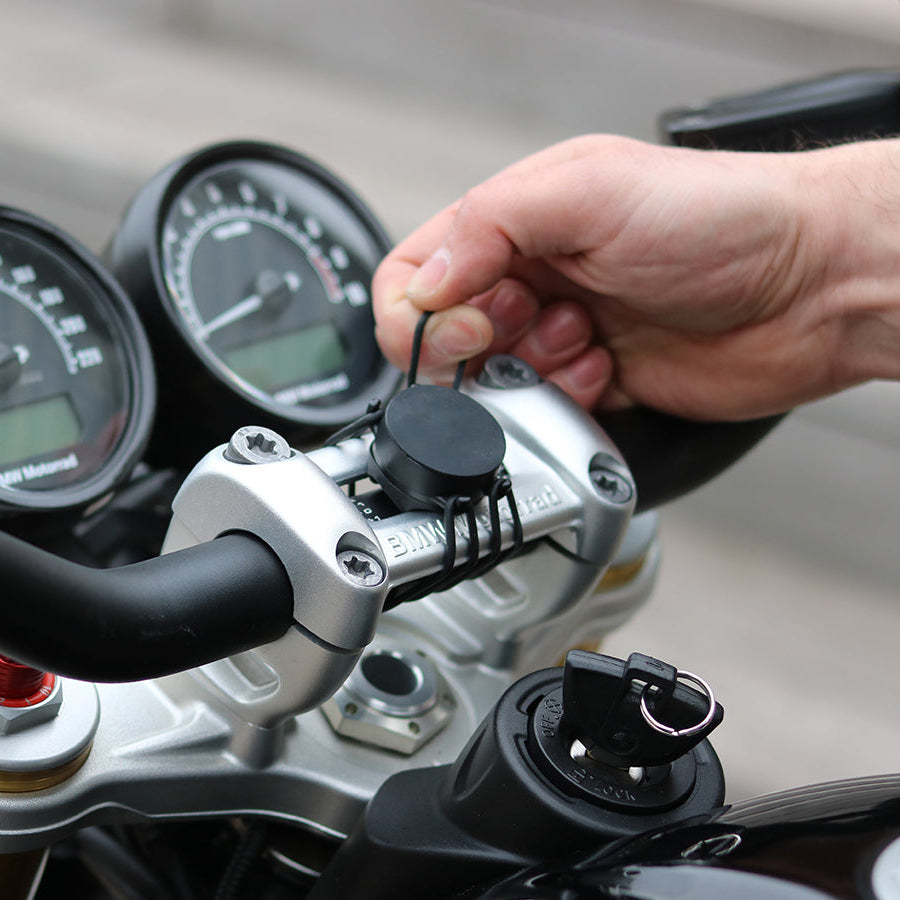 Cinghia elastica Shapeheart per moto - fissaggio sicuro. Vista in situazione che dimostra l'installazione delle cinghie su un manubrio di moto, perfetta per mantenere il supporto in posizione.