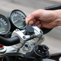 Cinghia elastica Shapeheart per moto - fissaggio sicuro. Vista in situazione che dimostra l'installazione delle cinghie su un manubrio di moto, perfetta per mantenere il supporto in posizione.